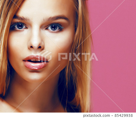 young pretty blonde real woman with hairstyle close up and makeup on pink background smiling 85429938