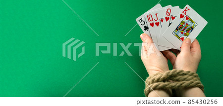 Hands with playing cards tied with a thick rope on a green felt table, gambling addiction Hands with playing cards tied with a thick rope on a green felt table, gambling addiction 85430256