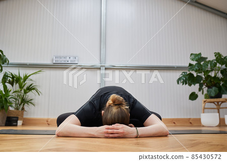 flexible woman lying on the envelope of a mat practicing yoga 85430572