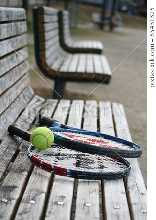 Tennis racket and ball on the bench 85431325