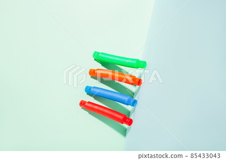 The straight folded pop tube stands leaning against the wall. Modern still life with antistress toy The straight folded pop tube stands leaning against the wall. Modern still life with antistress toy 85433043