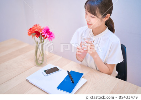 A young woman taking a break while drinking water A young woman taking a break while drinking water 85433479