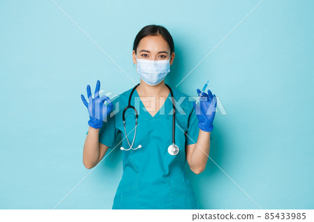 Covid-19, social distancing and coronavirus pandemic concept. Professional confident asian female nurse, doctor in medical mask and gloves, show okay gesture, hold syringe with vaccine Covid-19, social distancing and coronavirus pandemic concept. Professional confident asian female nurse, doctor in medical mask and gloves, show okay gesture, hold syringe with vaccine 85433985