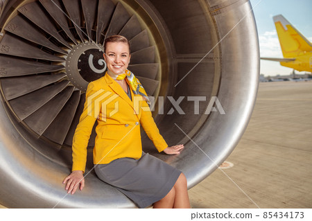 Joyful woman stewardess sitting on aircraft engine 85434173