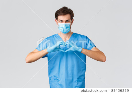 Covid-19, quarantine, hospitals and healthcare workers concept. Serious determined doctor or nurse in scrubs, medical mask and gloves, showing heart sign, care for patients, asking stay home safe 85436259