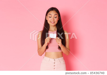 Beauty, fashion and lifestyle concept. Portrait of excited attractive asian girl in trendy clothes tempting to use credit card and buy something, likes shopping, standing pink background Beauty, fashion and lifestyle concept. Portrait of excited attractive asian girl in trendy clothes tempting to use credit card and buy something, likes shopping, standing pink background 85436740
