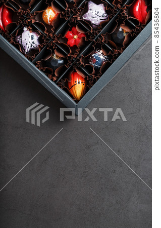 Handmade chocolates in a box on a dark background. 85436804