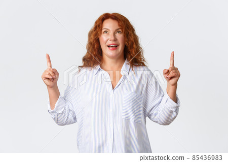 Wondered and amazed, upbeat middle-aged woman react to wonderful news, pointing and looking up with excited smile, reading banner, react to awesome promo offer, standing white background Wondered and amazed, upbeat middle-aged woman react to wonderful news, pointing and looking up with excited smile, reading banner, react to awesome promo offer, standing white background 85436983