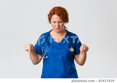 Medicine, healthcare and coronavirus concept. Frustrated and disappointed middle-aged female doctor, nurse looking with disgust and aversion down, grimacing, pointing fingers downwards 85437429