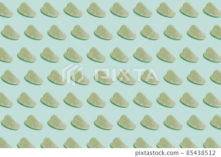 Pattern made with jade gua sha facial tool on pastel green background. Facial massage kit for lifting massage therapy made from natural stones, personal skin care anti-aging tools. 85438512