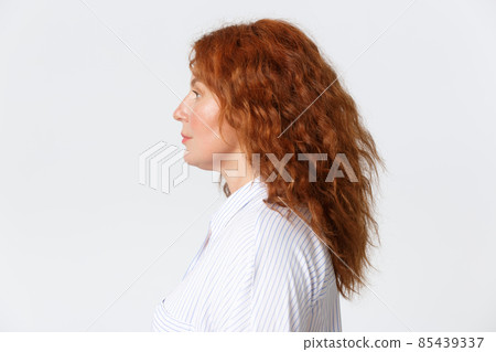 People, emotions and lifestyle concept. Close-up profile portrait of redhead middle-aged woman with curly medium hairstyle, looking left with casual face, standing white background 85439337