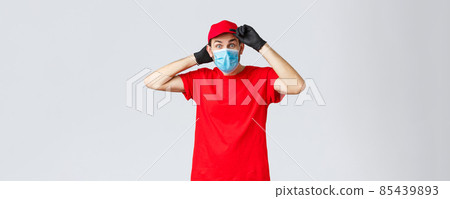 Groceries and packages delivery, covid-19, shopping concept. Excited surprised delivery man in red uniform, fix cap on head and staring interested camera, courier on duty during coronavirus 85439893