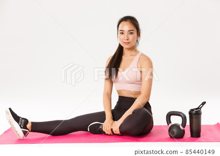 Woman practicing kettlebell squat with personal trainer at gym stock photo