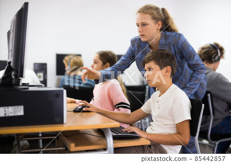 Teacher helping student with computer work Teacher helping student with computer work 85442857