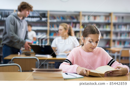 Young girl doing homework in library Young girl doing homework in library 85442859