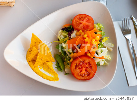 Salad with hummus and nachos served on plate 85443057