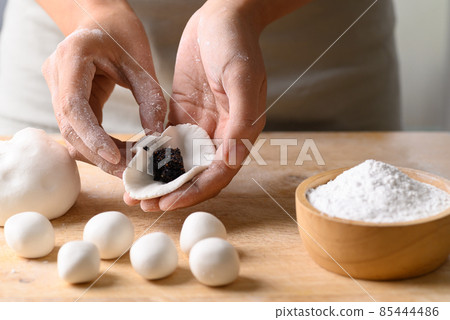 Hand making Tangyuan, Chinese dessert made of ball glutinous rice flour and filled with black sesame 85444486