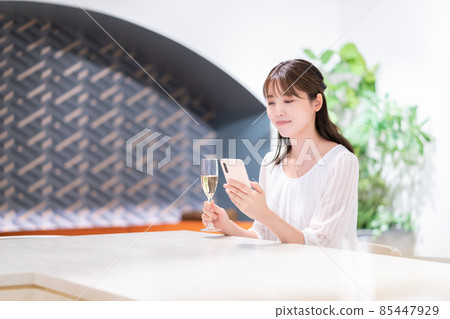 一位女士在咖啡廳喝香檳時看著智能手機 圖片合作:WEEK Shibadaimon(Sun Frontier Fudousan) 一位女士在咖啡廳喝香檳時看著智能手機 圖片合作:WEEK Shibadaimon(Sun Frontier Fudousan) 85447929