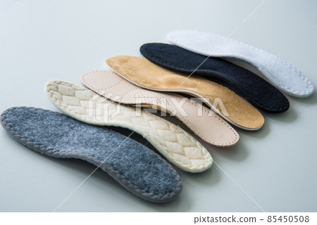 Studio photo of orthopedic insoles. A variety of orthopedic insoles are laid out in a row. Different colors and coatings: leather, cotton, microfiber. Studio photo of orthopedic insoles. A variety of orthopedic insoles are laid out in a row. Different colors and coatings: leather, cotton, microfiber. 85450508