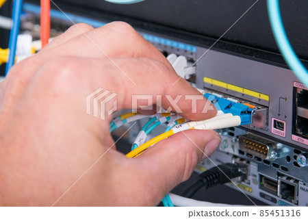 Hand of computer engineer connecting fiber optic cable in server Hand of computer engineer connecting fiber optic cable in server 85451316