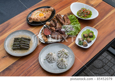 Festive feast with different dishes from Georgia, Armenia and Russia. Caucasian cuisine. Various delicious dishes on the wooden table.  85452079