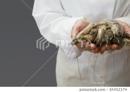 chef holding raw shrimps 85452374
