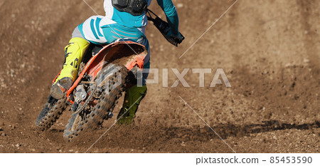 Racer boy on motorcycle participates in motocross race, active extreme sport, flying debris from a motocross in dirt track 85453590