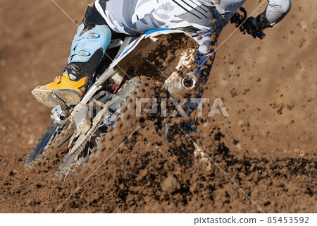 Racer boy on motorcycle participates in motocross race, active extreme sport, flying debris from a motocross in dirt track Racer boy on motorcycle participates in motocross race, active extreme sport, flying debris from a motocross in dirt track 85453592