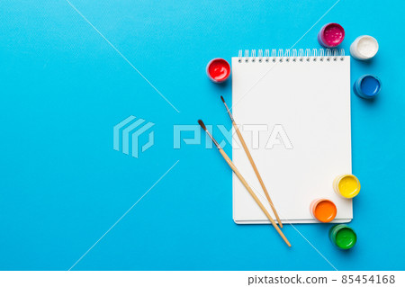 Album pages and paints, pencils, brush on a colored background. Top view with empty space. workplace for creativity. home teaching concept drawing Album pages and paints, pencils, brush on a colored background. Top view with empty space. workplace for creativity. home teaching concept drawing 85454168