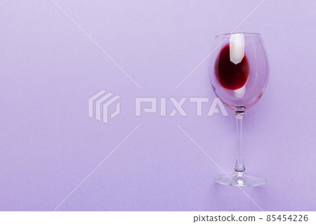 One glasses of red wine at wine tasting. Concept of red wine on colored background. Top view, flat lay design One glasses of red wine at wine tasting. Concept of red wine on colored background. Top view, flat lay design 85454226