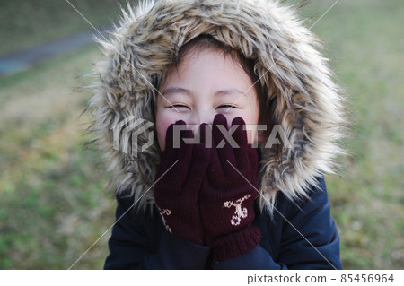 一個冷的女孩吹在她的手上 一個冷的女孩吹在她的手上 85456964