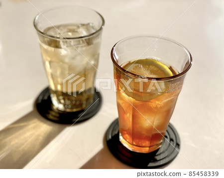 A landscape of black coasters laid on two glasses of iced tea and ginger ale 85458339