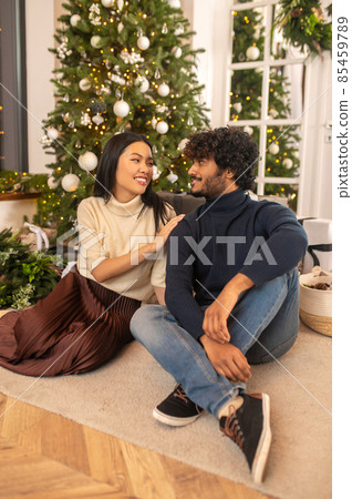 Woman touching man looking at each other sitting on floor 85459789