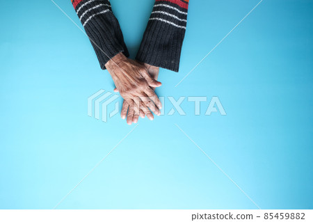 top view of hands of a elderly person on blue background top view of hands of a elderly person on blue background 85459882