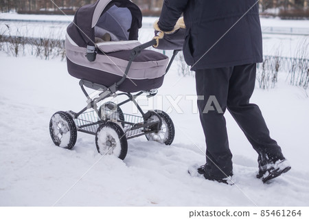Baby stroller wheel on snowy road in winter. Baby stroller wheel on snowy road in winter. 85461264