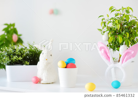 Colored eggs, cute little bunny and rabbit ears on the table on Easter day. Celebrating Easter at spring. Painting eggs. 85461332