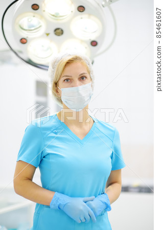 Portrait of female surgeon wearing in medical face mask and protective gloves. Doctor is preparing for surgery in operation room. Portrait of female surgeon wearing in medical face mask and protective gloves. Doctor is preparing for surgery in operation room. 85461607