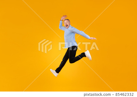 Excited mature man jumping up at orange studio Excited mature man jumping up at orange studio 85462332