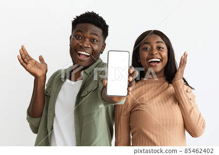 Emotional african american couple showing smartphone with empty screen, mockup Emotional african american couple showing smartphone with empty screen, mockup 85462402