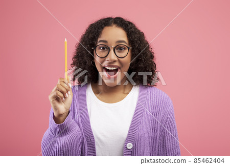 Excited black lady raising pencil up, having creative idea or inspiration on pink studio background Excited black lady raising pencil up, having creative idea or inspiration on pink studio background 85462404