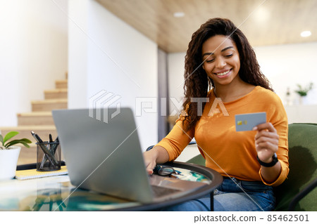 Happy woman holding debit credit card, using pc Happy woman holding debit credit card, using pc 85462501