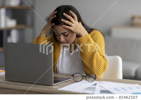 Stressful job, burnout concept. Stressed arab lady working on laptop and touching head, having problem at workplace Stressful job, burnout concept. Stressed arab lady working on laptop and touching head, having problem at workplace 85462507