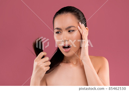 Worried naked asian woman checking her hair ends Worried naked asian woman checking her hair ends 85462530