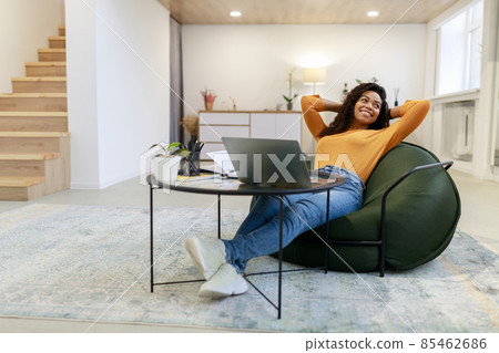 Smiling black woman leaning back sitting at desk Smiling black woman leaning back sitting at desk 85462686