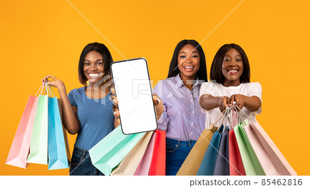 Online Sales. Thre Black Females With Bright Shopping Bags Showing Blank Smartphone Online Sales. Thre Black Females With Bright Shopping Bags Showing Blank Smartphone 85462816