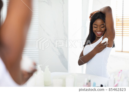 Smiling Black Lady Applying Roller Deodorant To Armpit Zone In Bathroom Smiling Black Lady Applying Roller Deodorant To Armpit Zone In Bathroom 85462823
