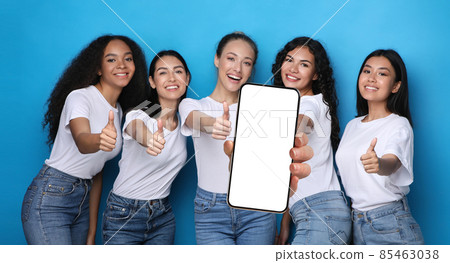 Happy women showing empty smartphone screen and thumbs up 85463038