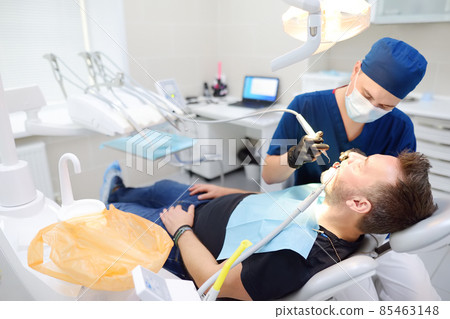 Dentist and patient at medical center. Doctor treats a mature man teeth with dental drill. Orthodontist and prosthetics appointment. Dentist and patient at medical center. Doctor treats a mature man teeth with dental drill. Orthodontist and prosthetics appointment. 85463148