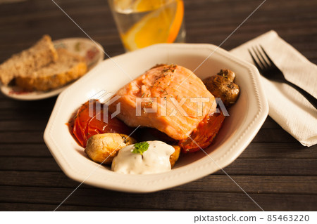 simmered slice of salmon with tomato spinon and coconut sauce in a white bowl simmered slice of salmon with tomato spinon and coconut sauce in a white bowl 85463220