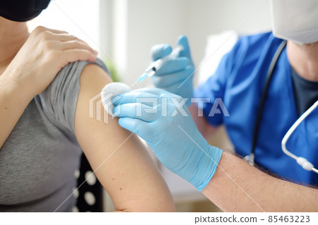 Doctor or nurse is preparing to give a injection vaccine against covid-19 to a woman. Mass vaccination of the population will help stop spread of coronavirus in the world. Doctor or nurse is preparing to give a injection vaccine against covid-19 to a woman. Mass vaccination of the population will help stop spread of coronavirus in the world. 85463223
